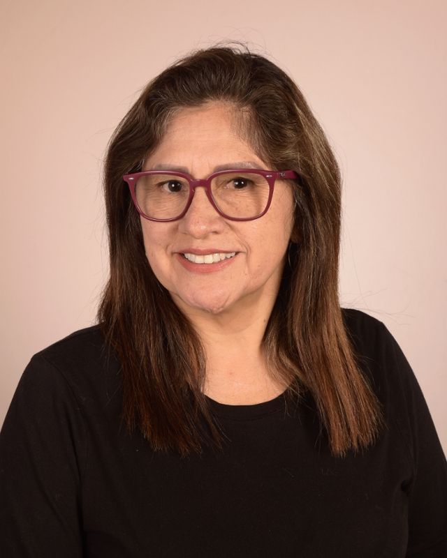 A woman wearing glasses and a black shirt is smiling for the camera.