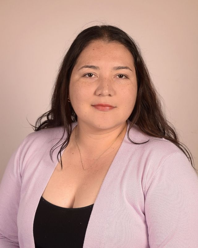 A woman is wearing a purple sweater and a black top.