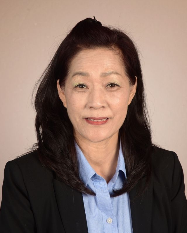A woman in a suit and blue shirt is smiling for the camera.