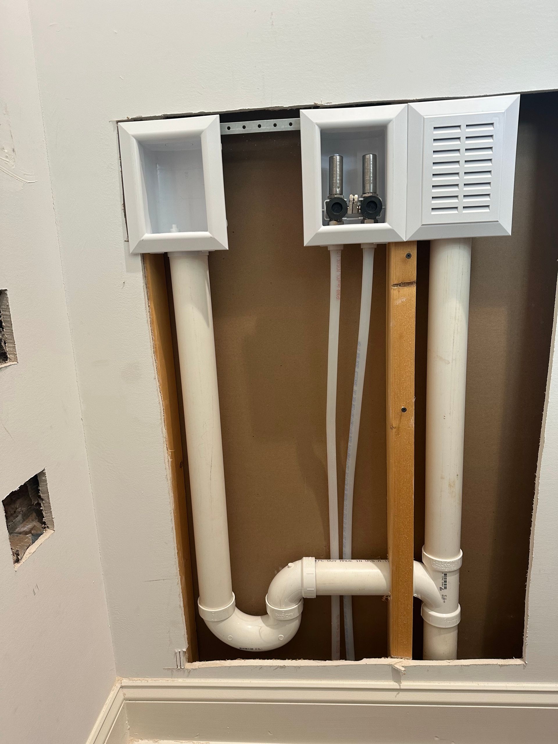 Laundry room water and drain pipes with electrical outlet boxes mounted in wall.