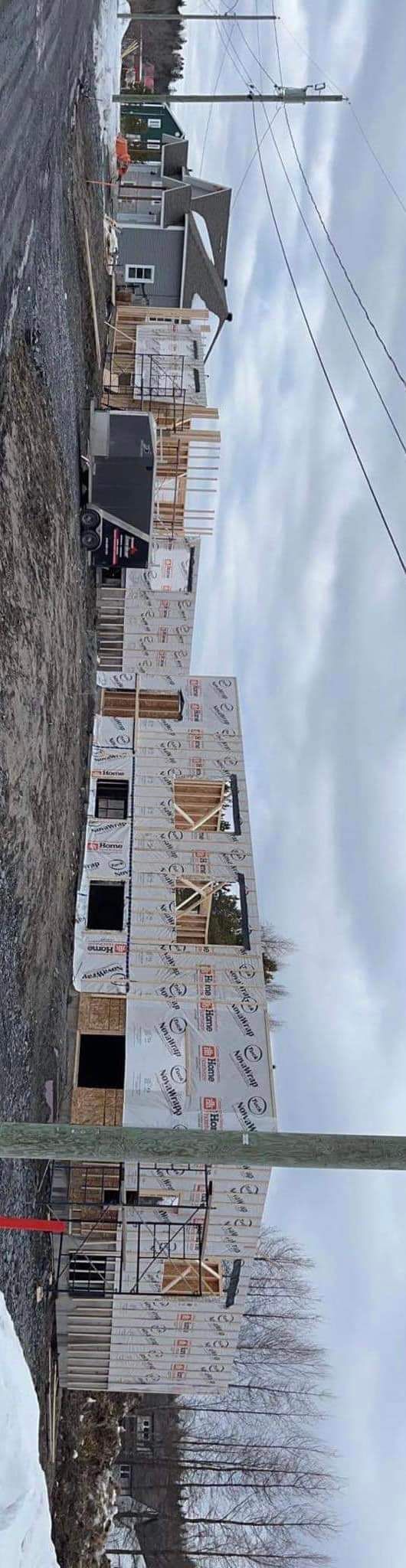 Chantier par temps nuageux. Bâtiments blancs en construction et chemin de terre dans un paysage hivernal.