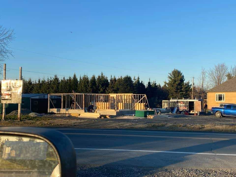 Chantier de construction avec charpente en bois, matériaux et un camion bleu.