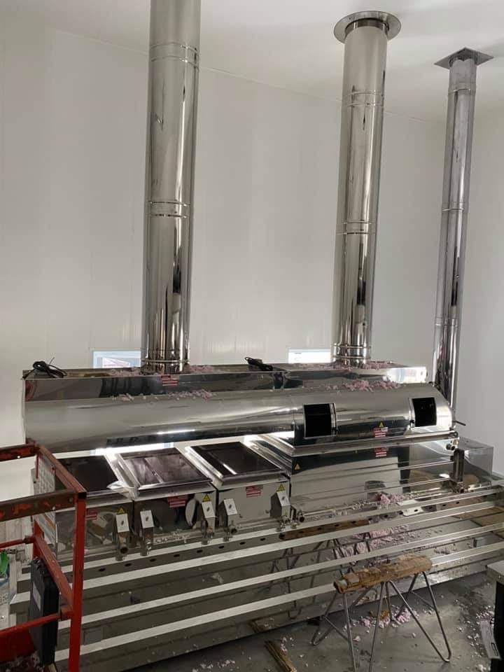 Équipement de cuisine commerciale en acier inoxydable avec trois grands conduits d'évacuation.