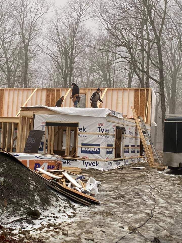Des ouvriers du bâtiment travaillent sur le toit d'une maison en construction, en hiver.