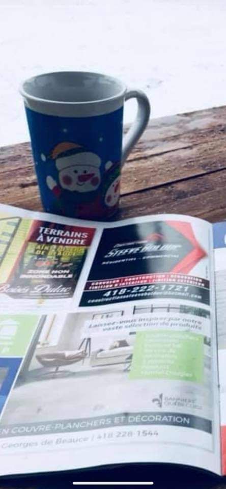 Mug bleu orné d'un bonhomme de neige sur un journal publicitaire, posé sur une surface en bois.