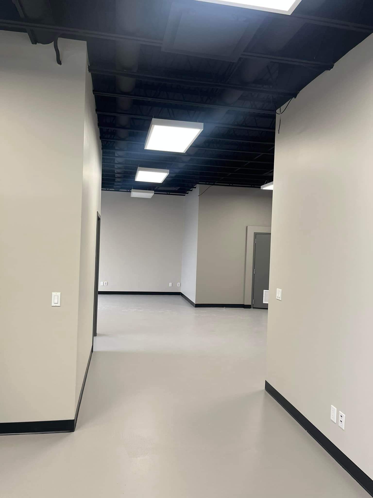 Espace intérieur vide avec murs gris, plafond noir et éclairage encastré.
