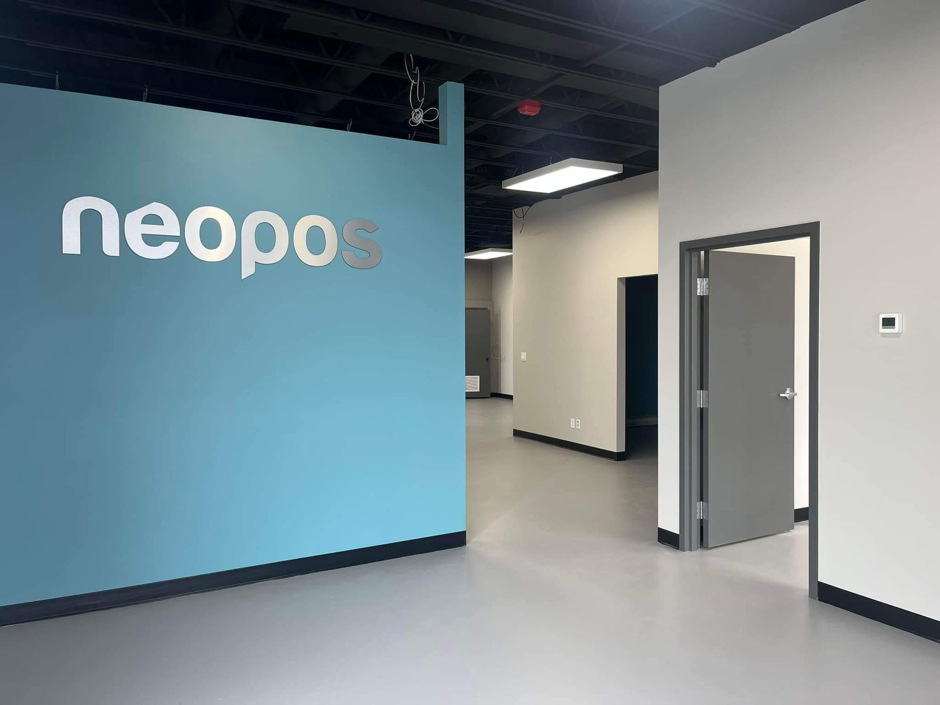 Un hall d'entrée de bureau moderne avec un mur d'accent bleu orné du logo « neopos ».