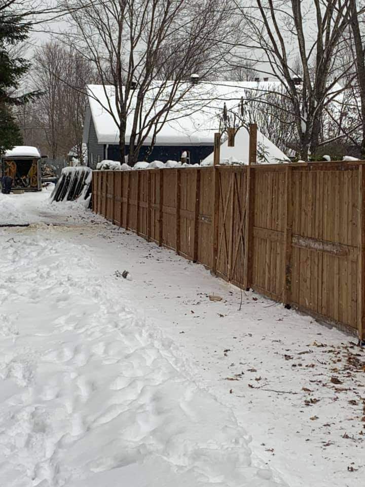 Jardin enneigé avec clôture en bois. Scène d'hiver avec sol et arbres recouverts de neige.
