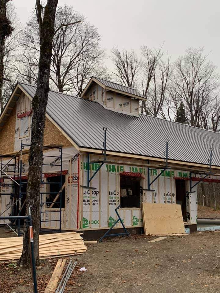 Un bâtiment en construction avec un toit en métal gris et des échafaudages.