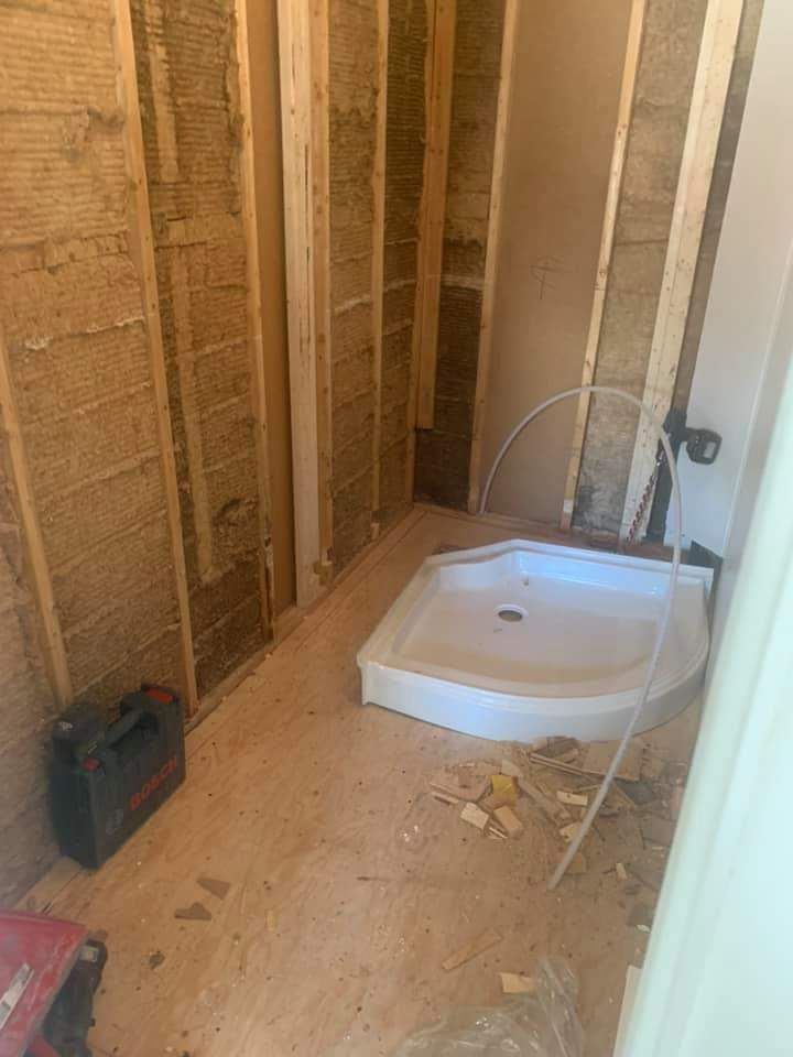 Salle de bain en construction, avec ossature bois, isolation et receveur de douche installés.