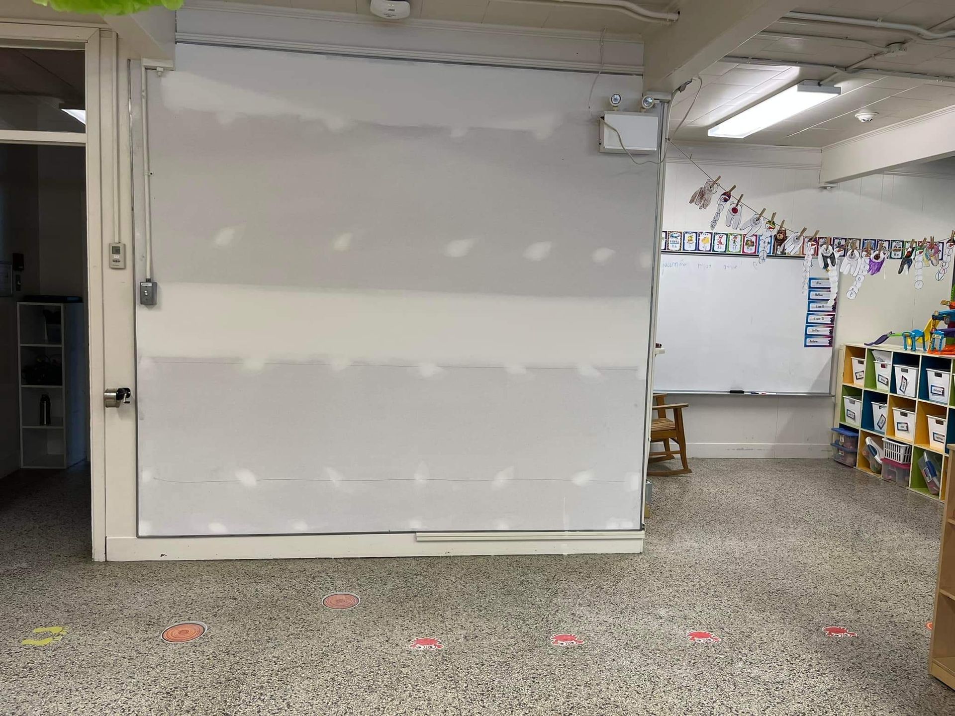 Salle de classe avec un mur inachevé et un tableau blanc.