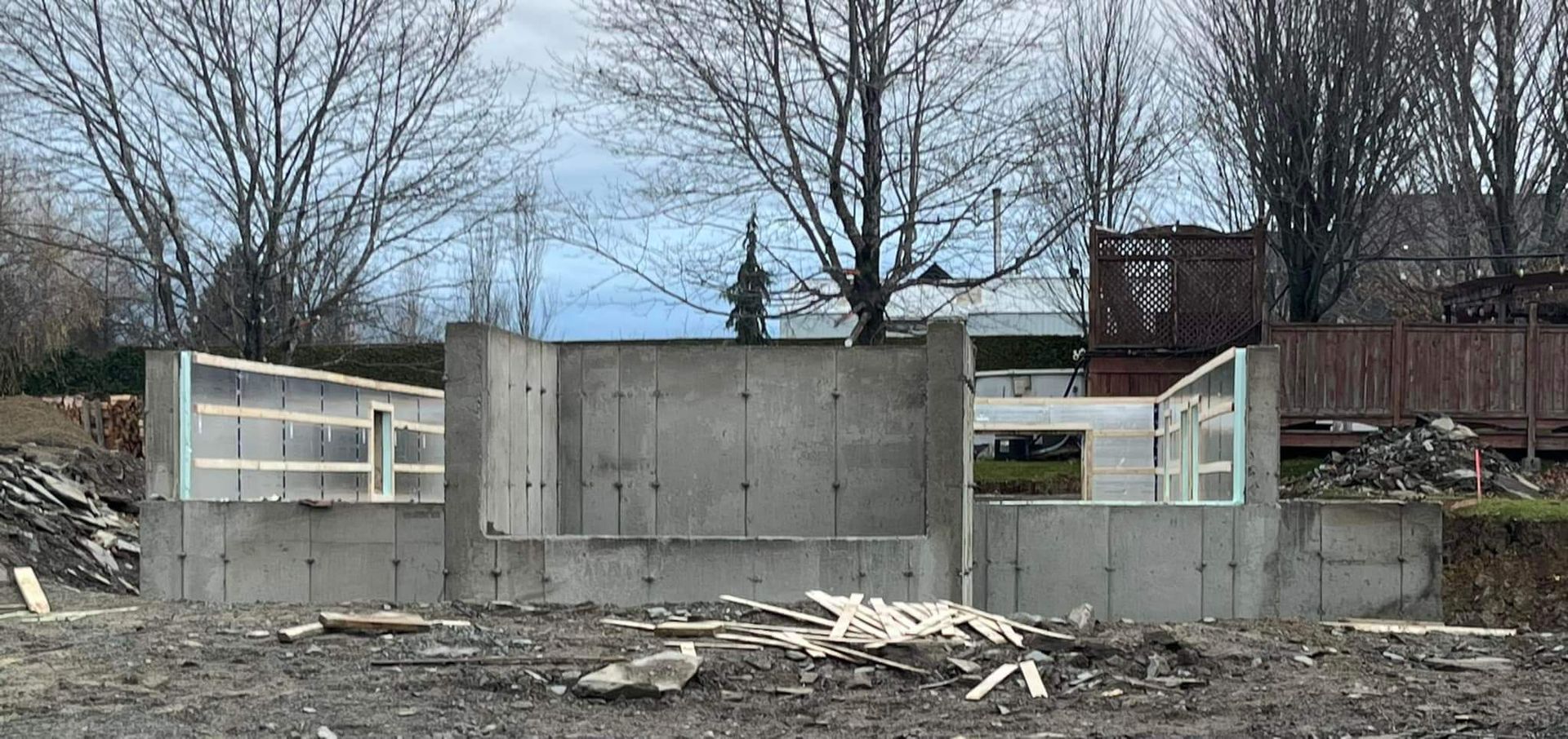 Fondations en béton d'un bâtiment en construction, avec ossature bois pour les fenêtres.