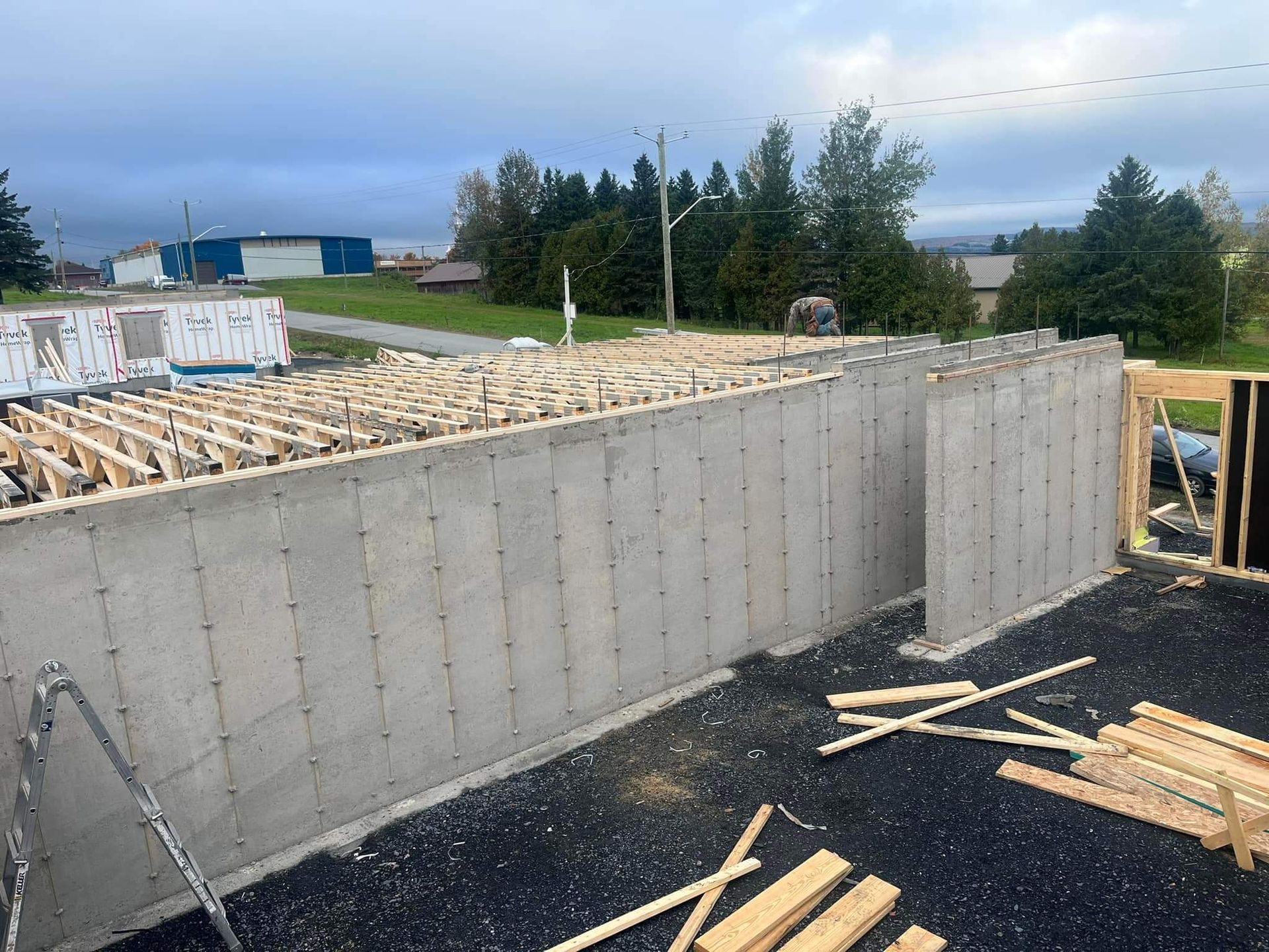 Murs de fondation en béton en construction, avec une charpente en bois et un ciel nuageux en arrière-plan.