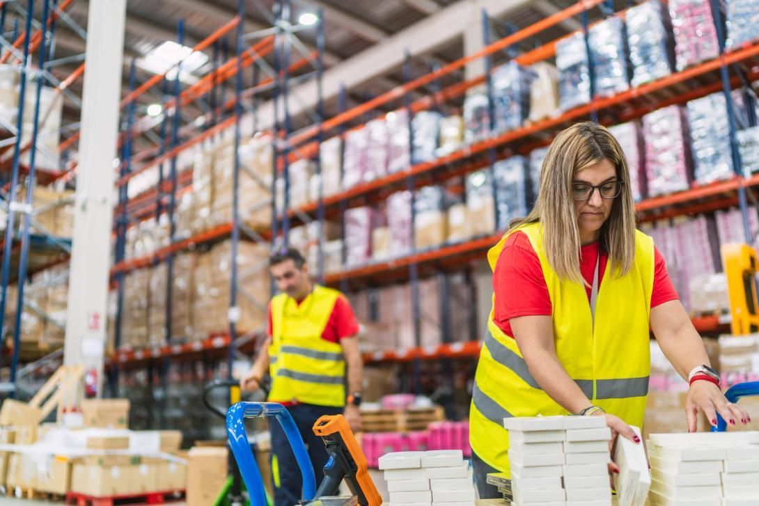Warehouse workers packing inventory in a modern fulfillment center with warehouse shelving visible