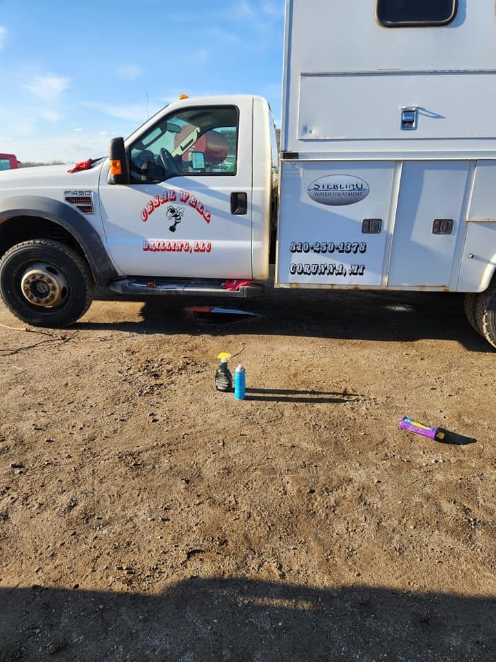 A man is standing in the dirt next to a red truck.