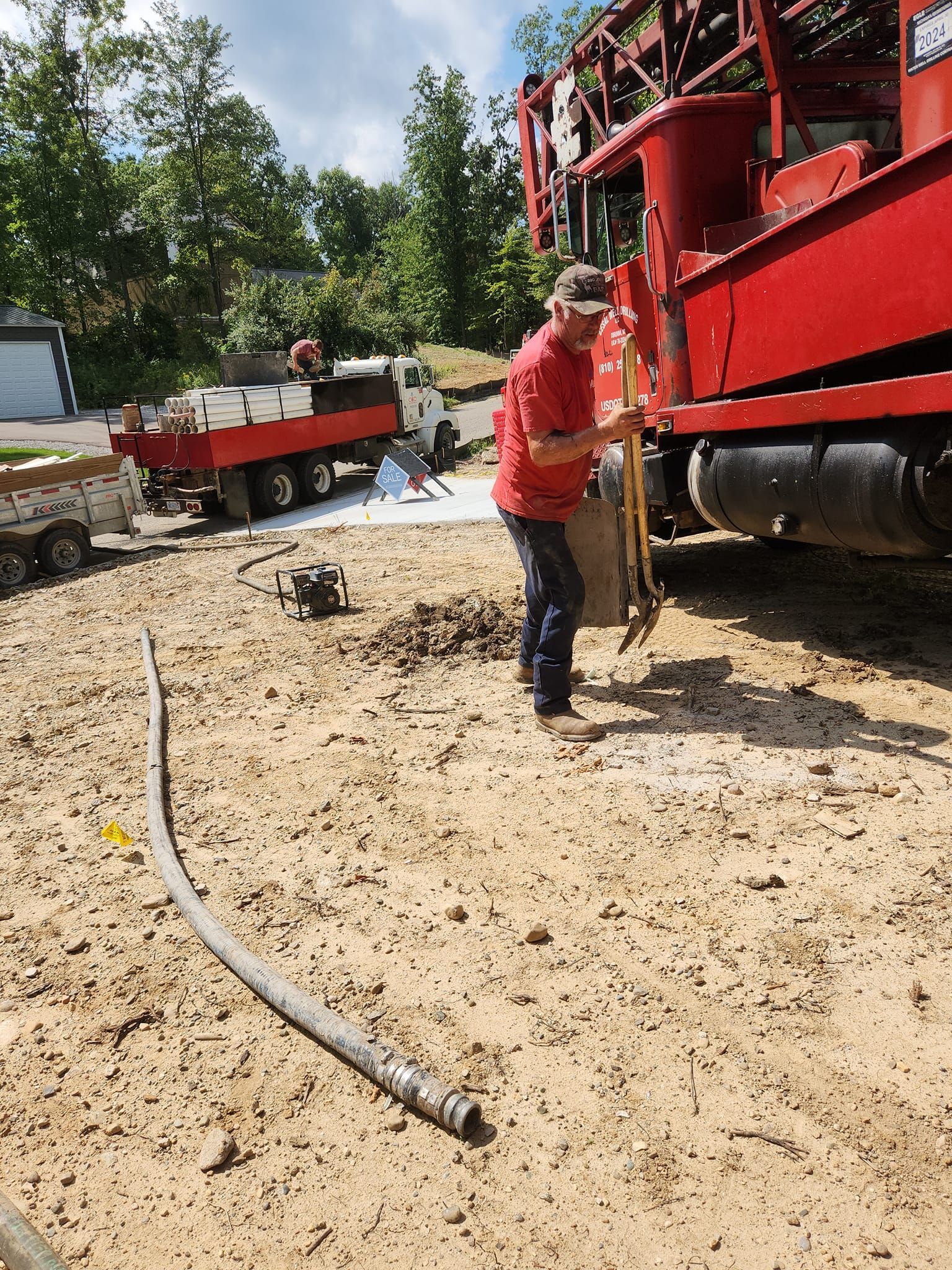 A man is standing in the dirt next to a red truck.