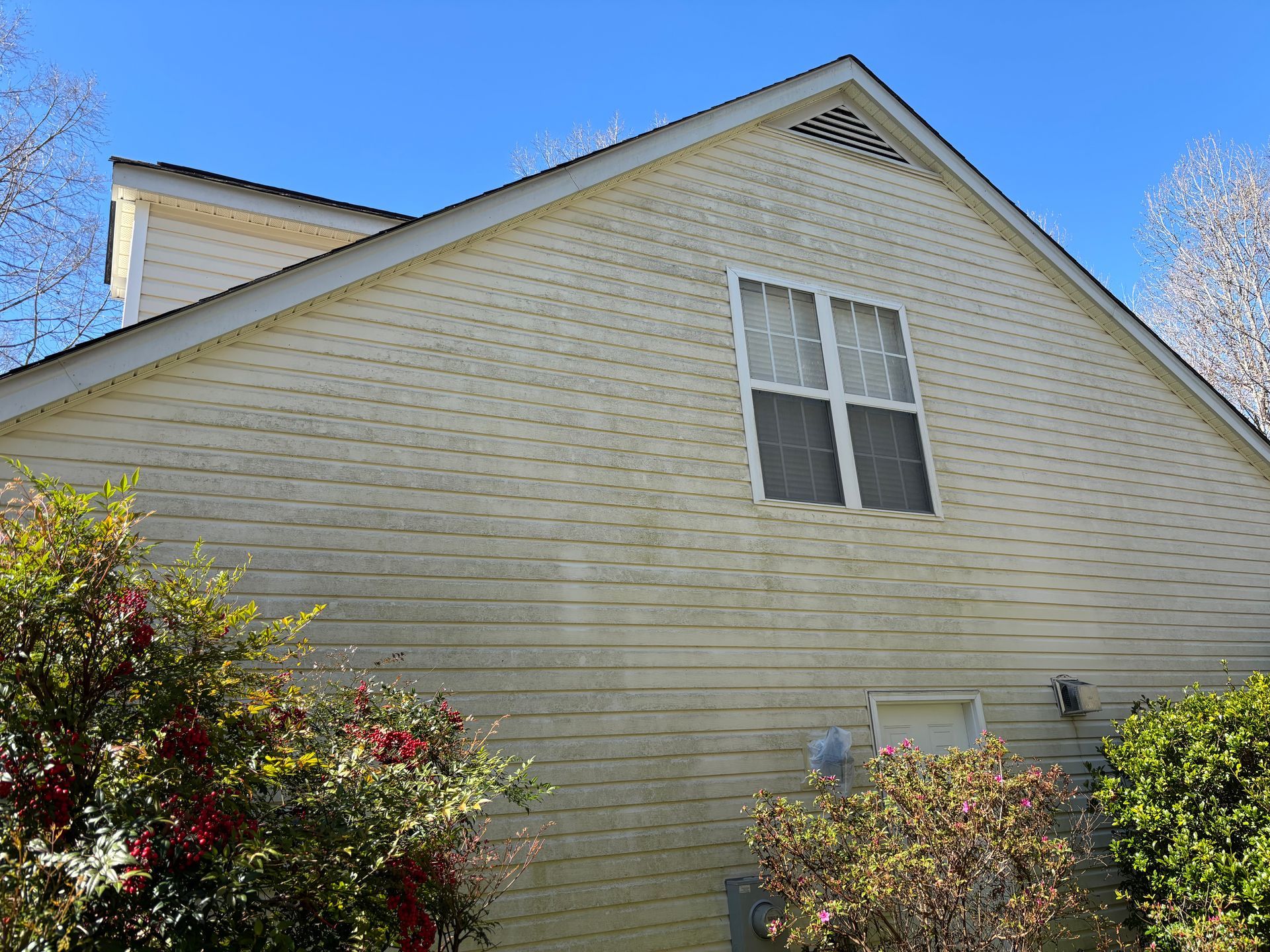 Windows Gutters LLC - Tan house with white trim and a window, against a blue sky.