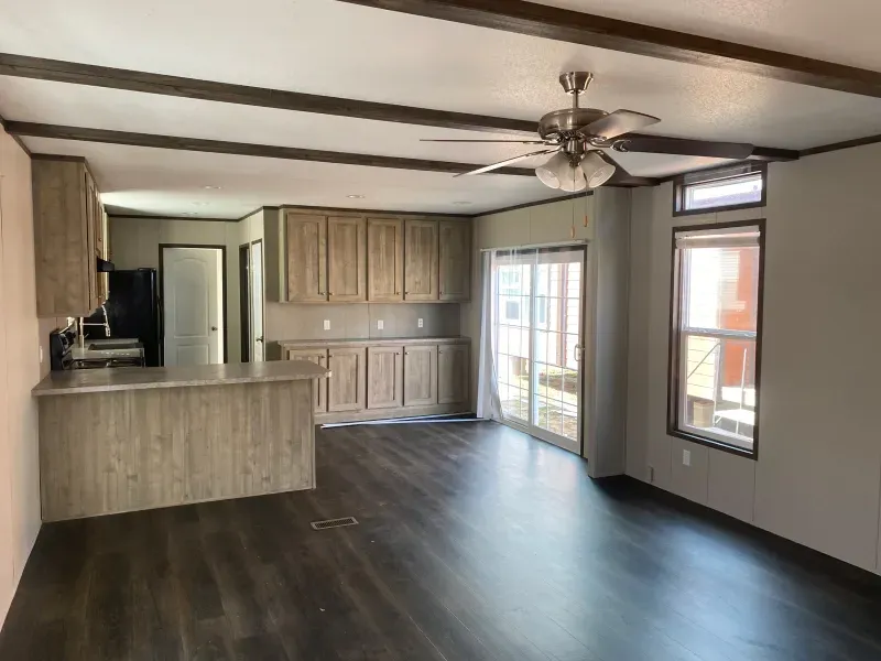 A living room with hardwood floors and a ceiling fan in a mobile home.