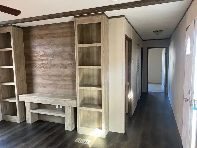 A hallway in a house with wooden shelves and a ceiling fan.