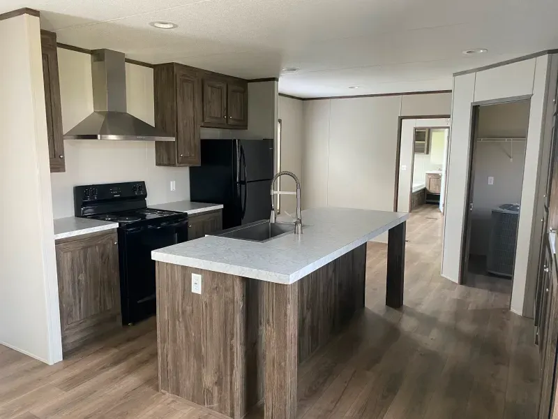 A kitchen with a large island , stove , refrigerator and sink.