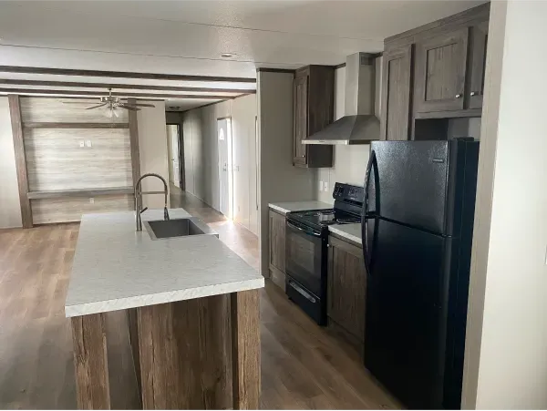 A kitchen with a black refrigerator , stove , sink and cabinets.