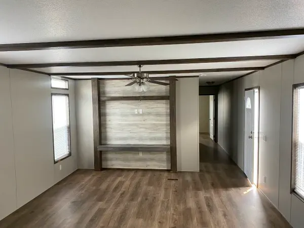 A living room in a mobile home with hardwood floors and a ceiling fan.