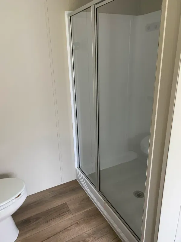 A bathroom with a toilet and a walk in shower.