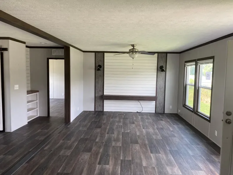 An empty living room with a wooden floor and a ceiling fan.