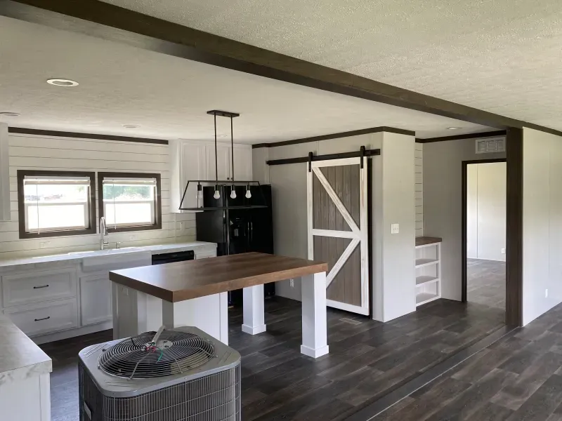 A kitchen in a mobile home with a sliding barn door and a table.