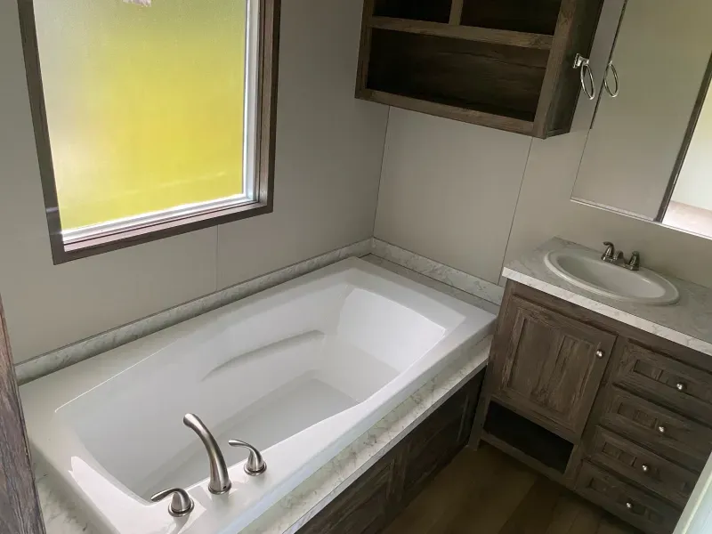 A bathroom with a bathtub , sink , mirror and window.