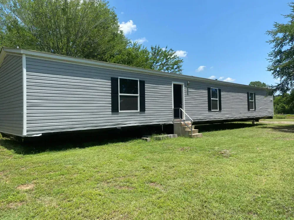 A mobile home is parked in a grassy field.