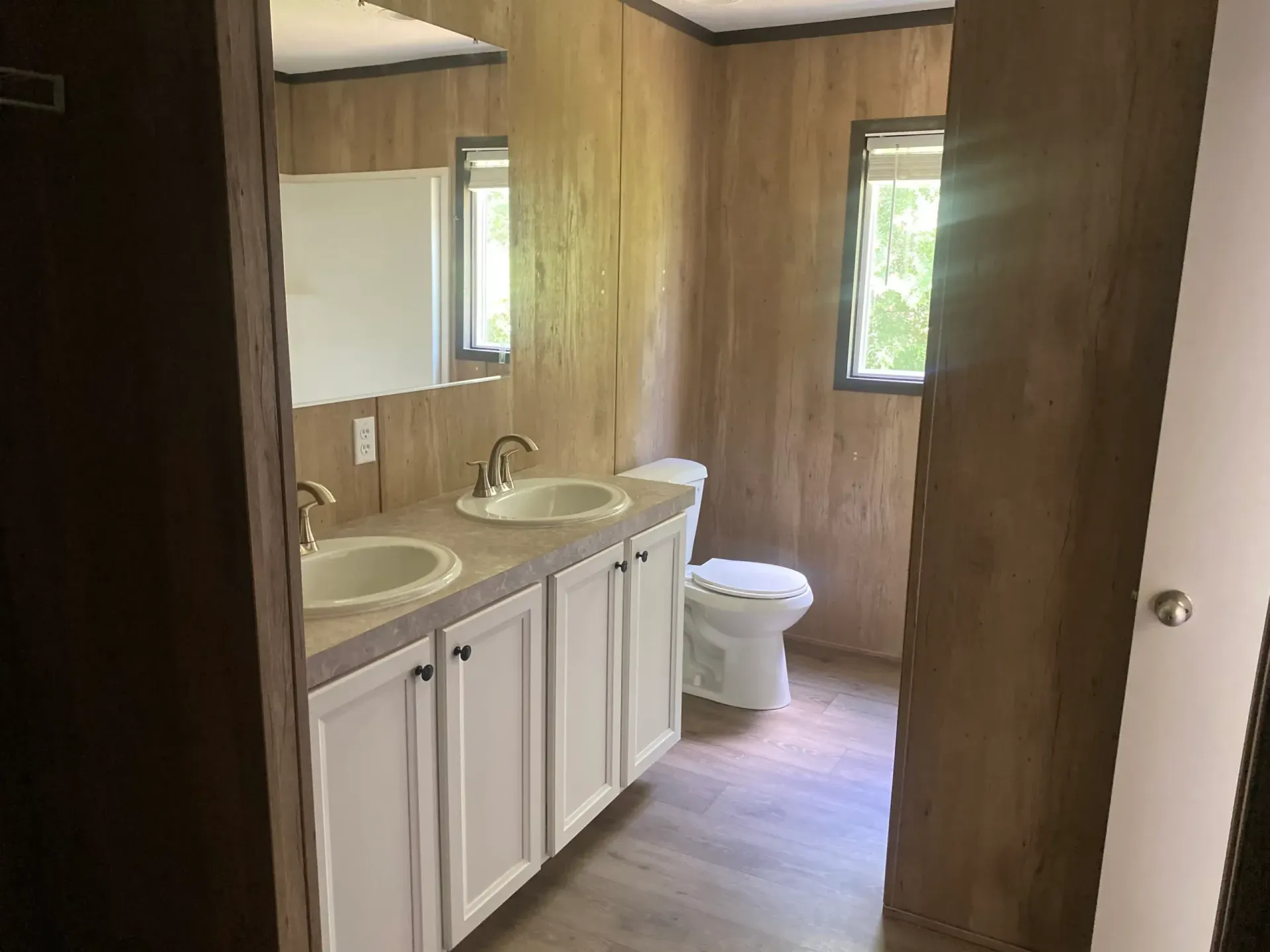 A bathroom with two sinks , a toilet and a mirror.