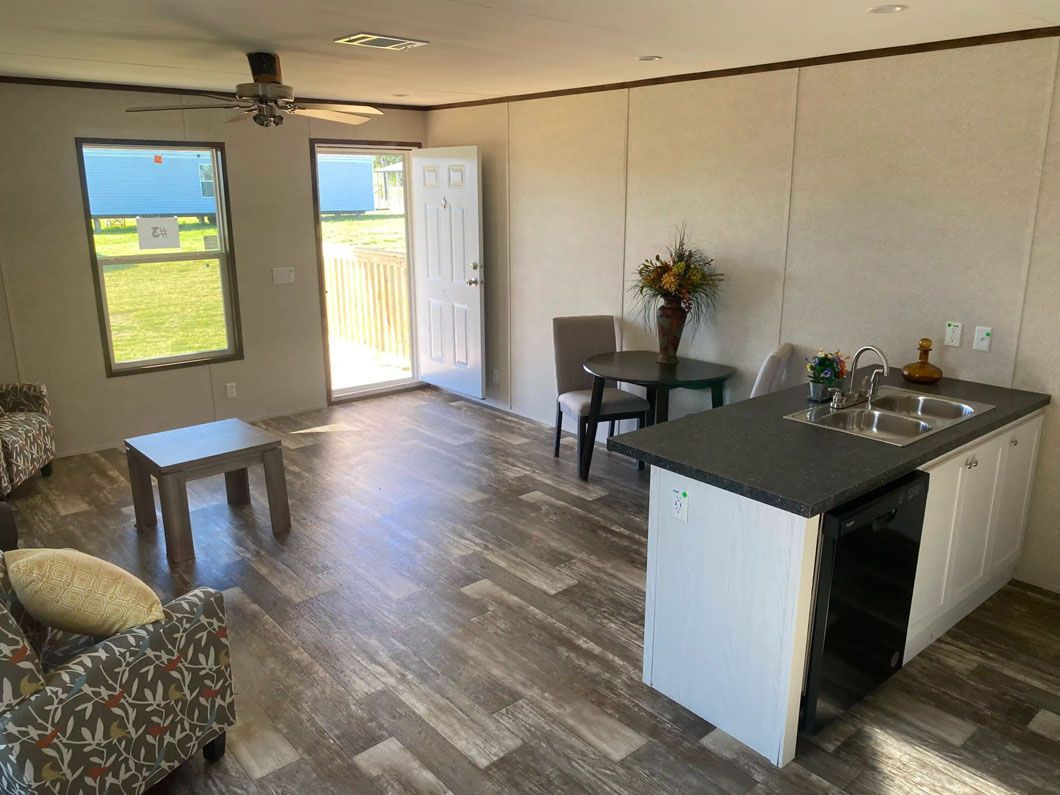 A living room with a table and chairs and a kitchen with a sink.