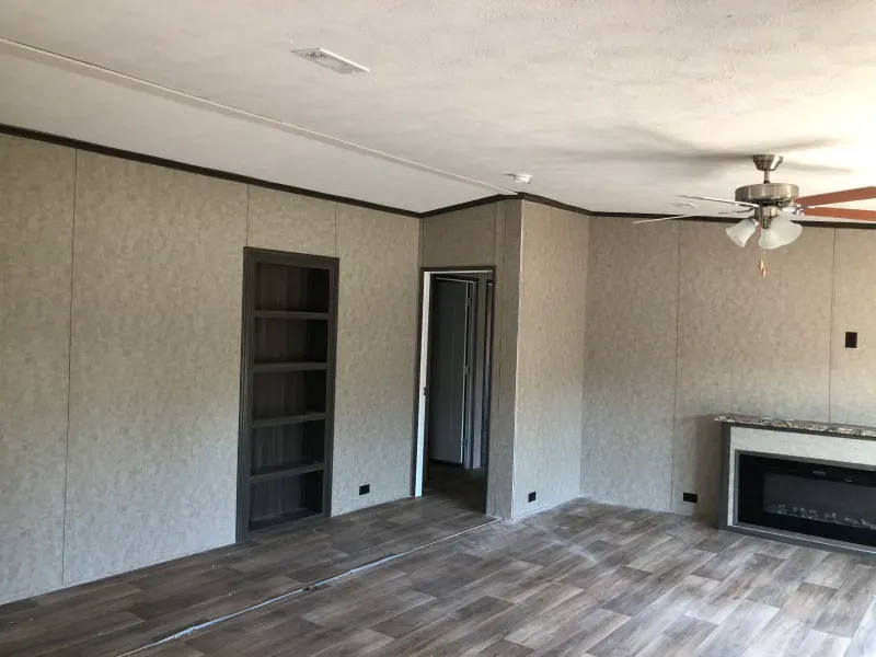 An empty living room with a fireplace and a ceiling fan.