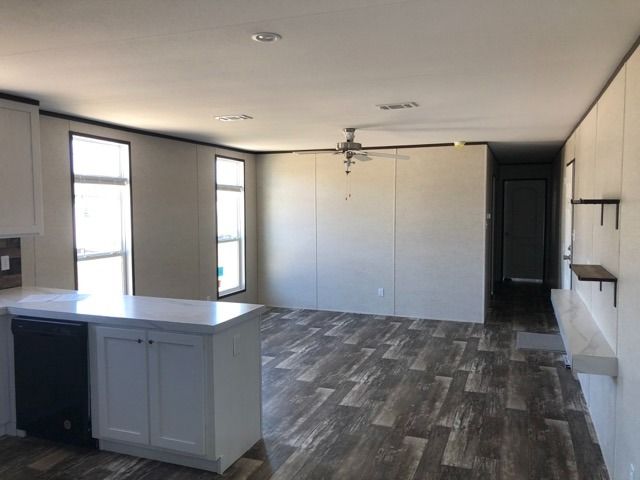 An empty room with a kitchen and a ceiling fan.