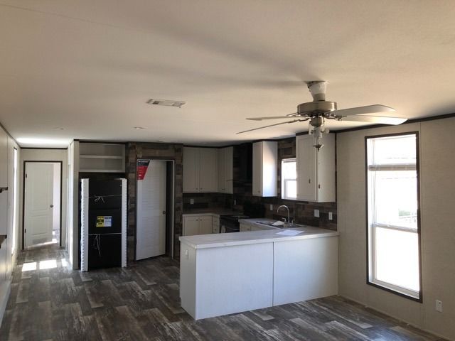 A kitchen with a refrigerator and a ceiling fan