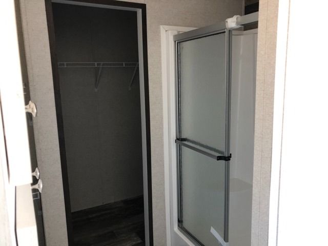 A bathroom with a shower door and a closet