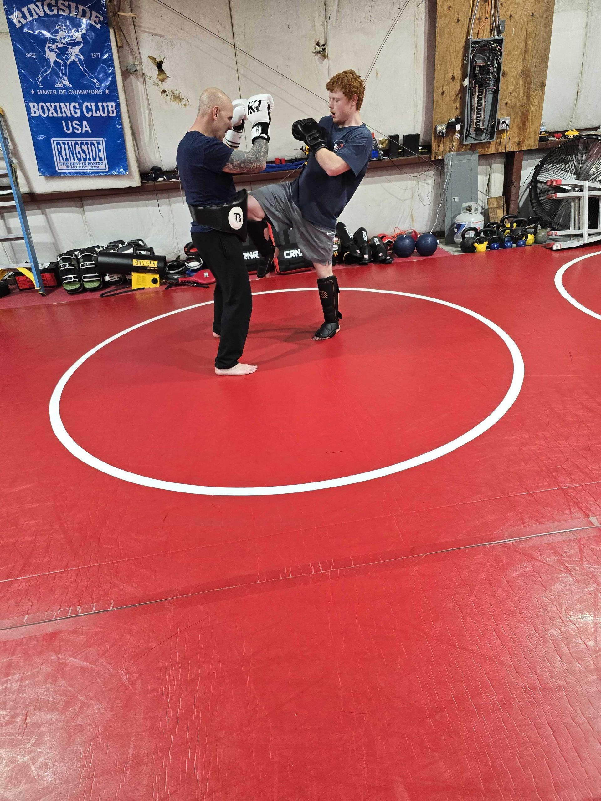 Adult students hitting pads at Roberts Family Mixed Martial Arts in Orange, MA, building fitness.