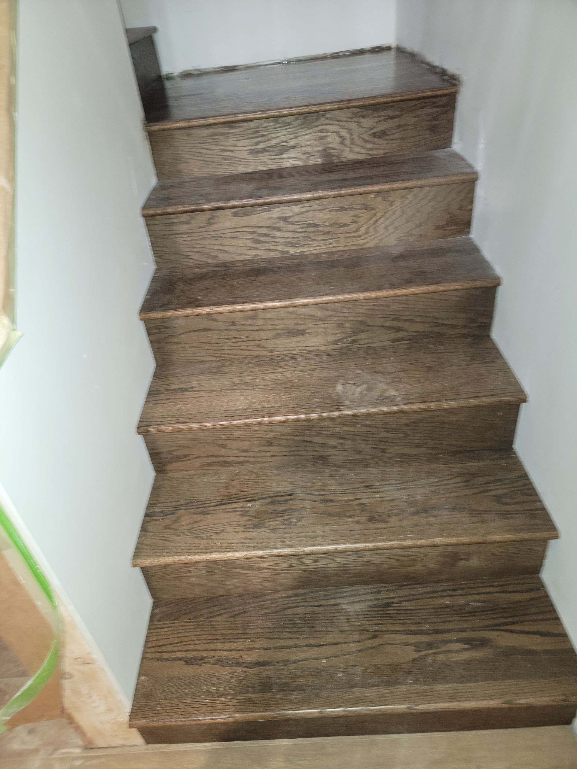 Narrow carpeted staircase with brown steps and white walls leading upward