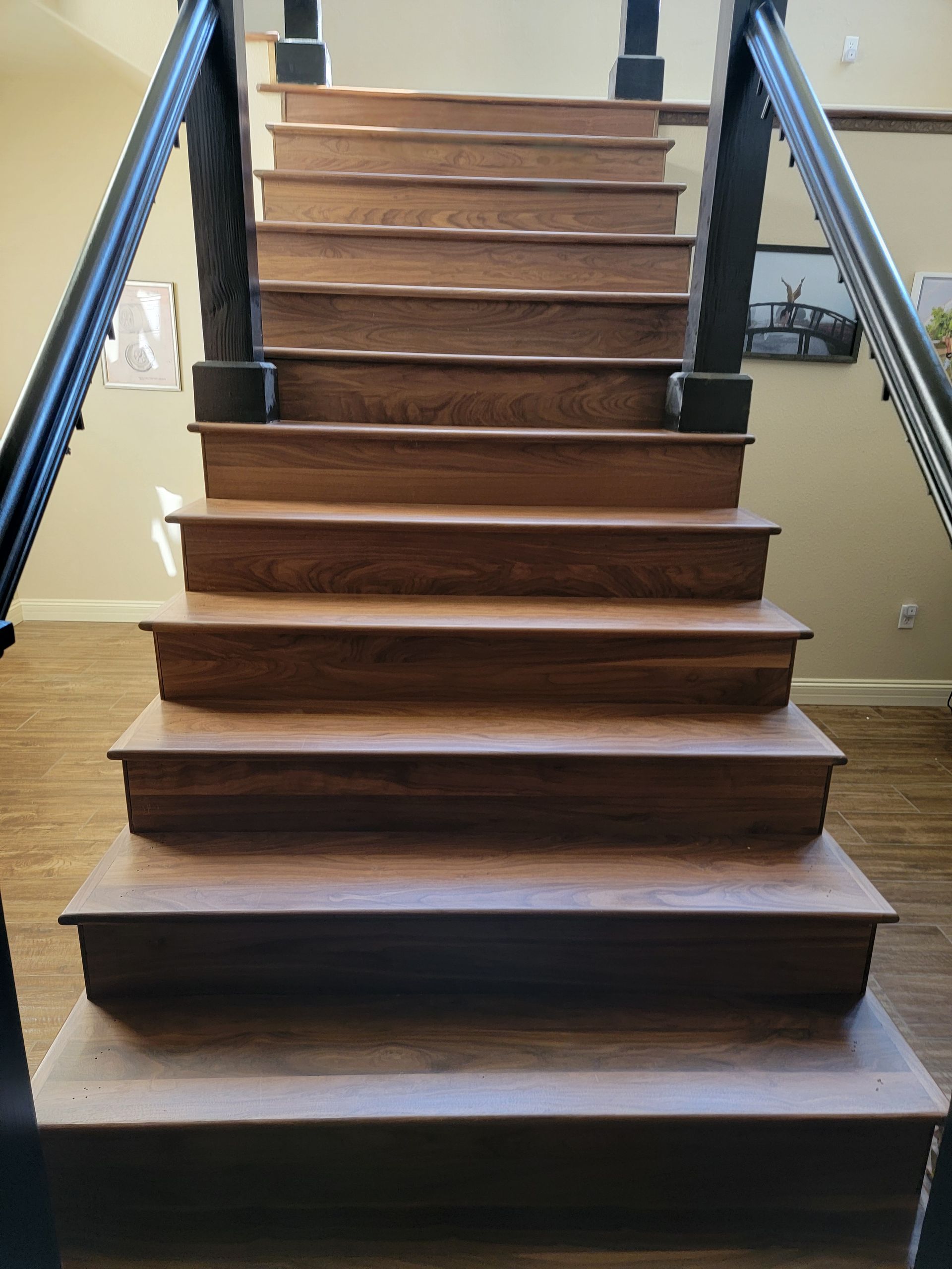 Wooden staircase with dark railings, viewed from the bottom inside a home.