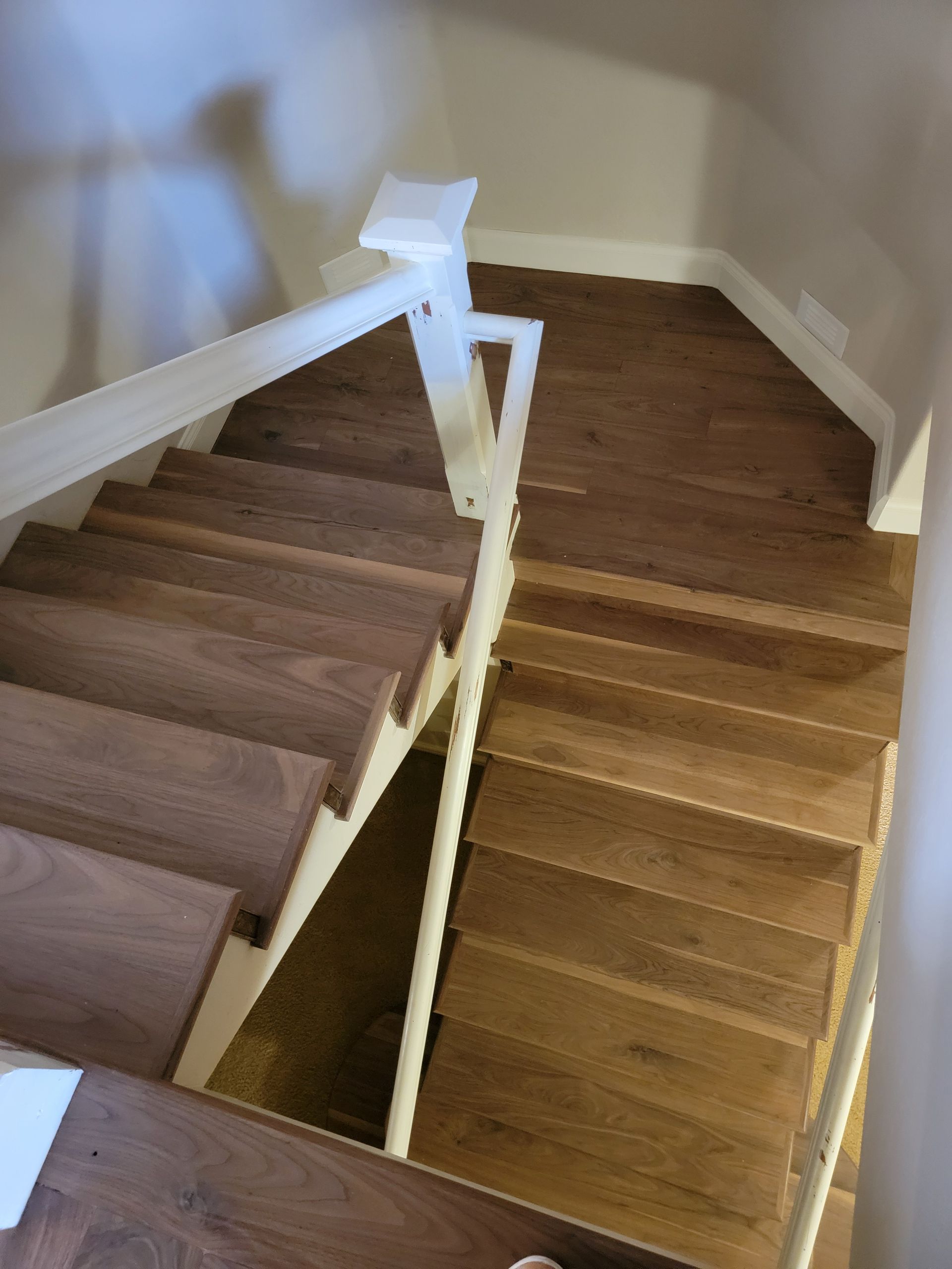 Staircase with wooden steps and white railings, viewed from the top looking down two flights. Staircase with wooden steps and white railings, viewed from the top looking down two flights.