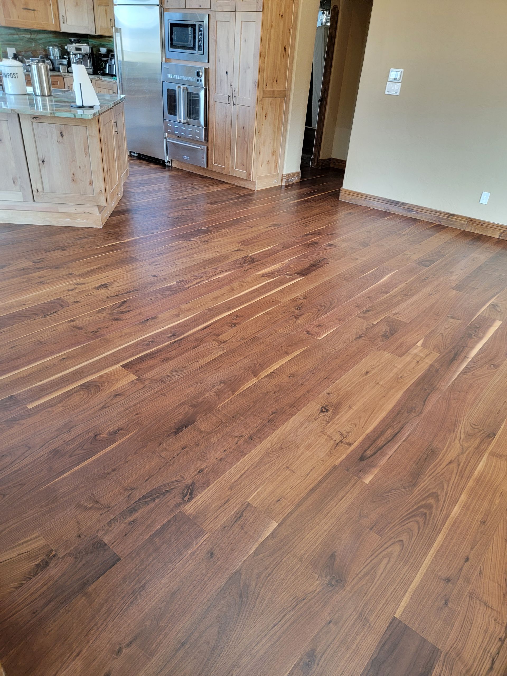 Spacious kitchen and living area with hardwood floors, wood cabinets, and stainless steel appliances