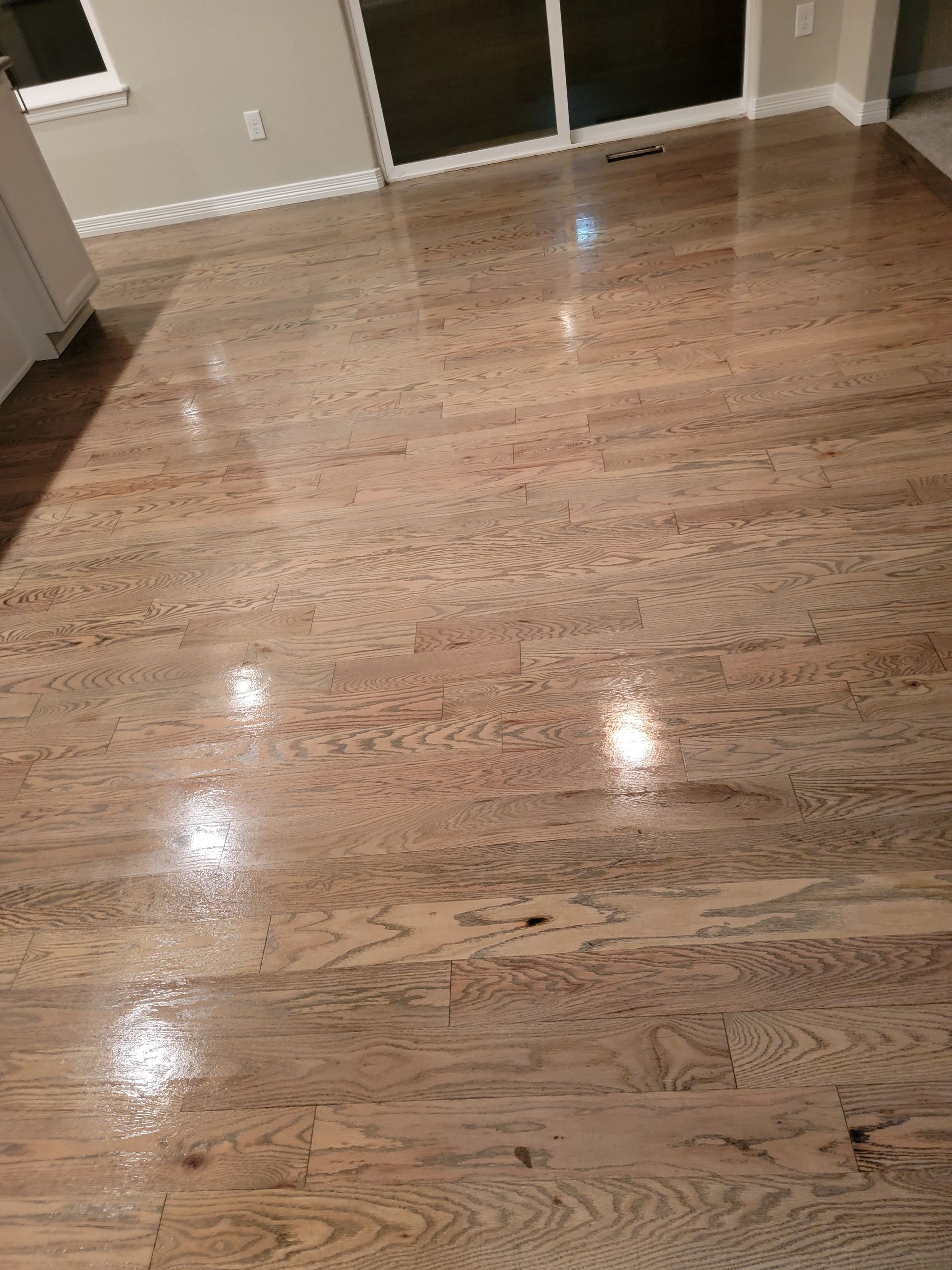 Polished hardwood floor in an empty room with reflections from overhead lights