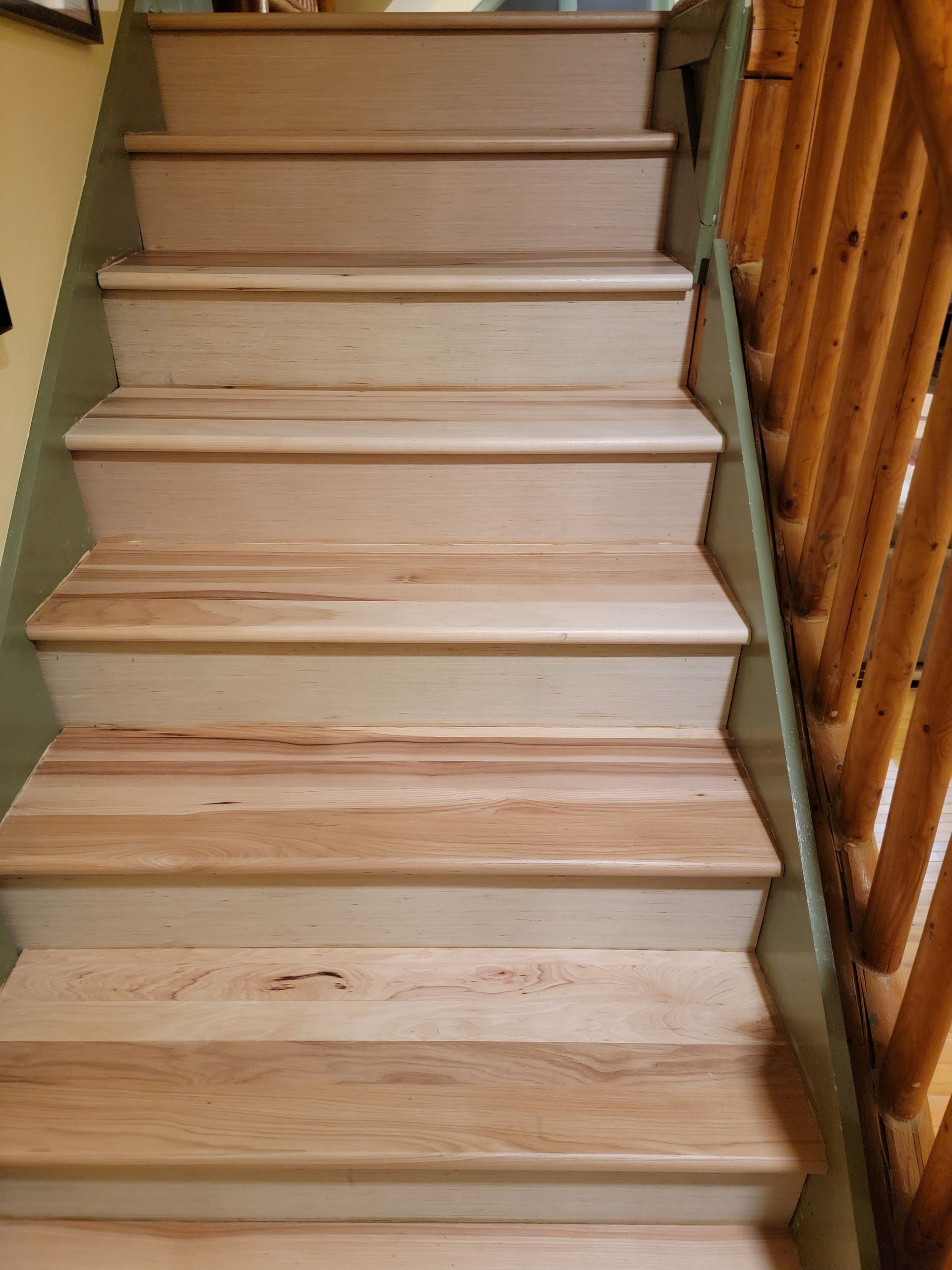 Wooden staircase with light steps and a brown railing indoors