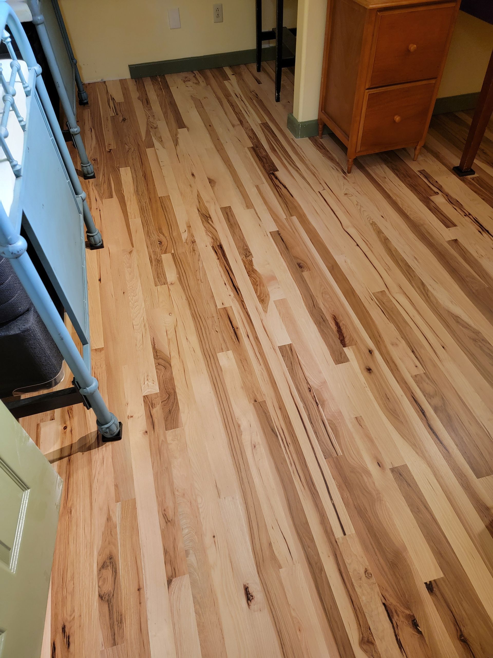 Striped wood floor in a hallway or room, viewed from above with cabinets along the walls.