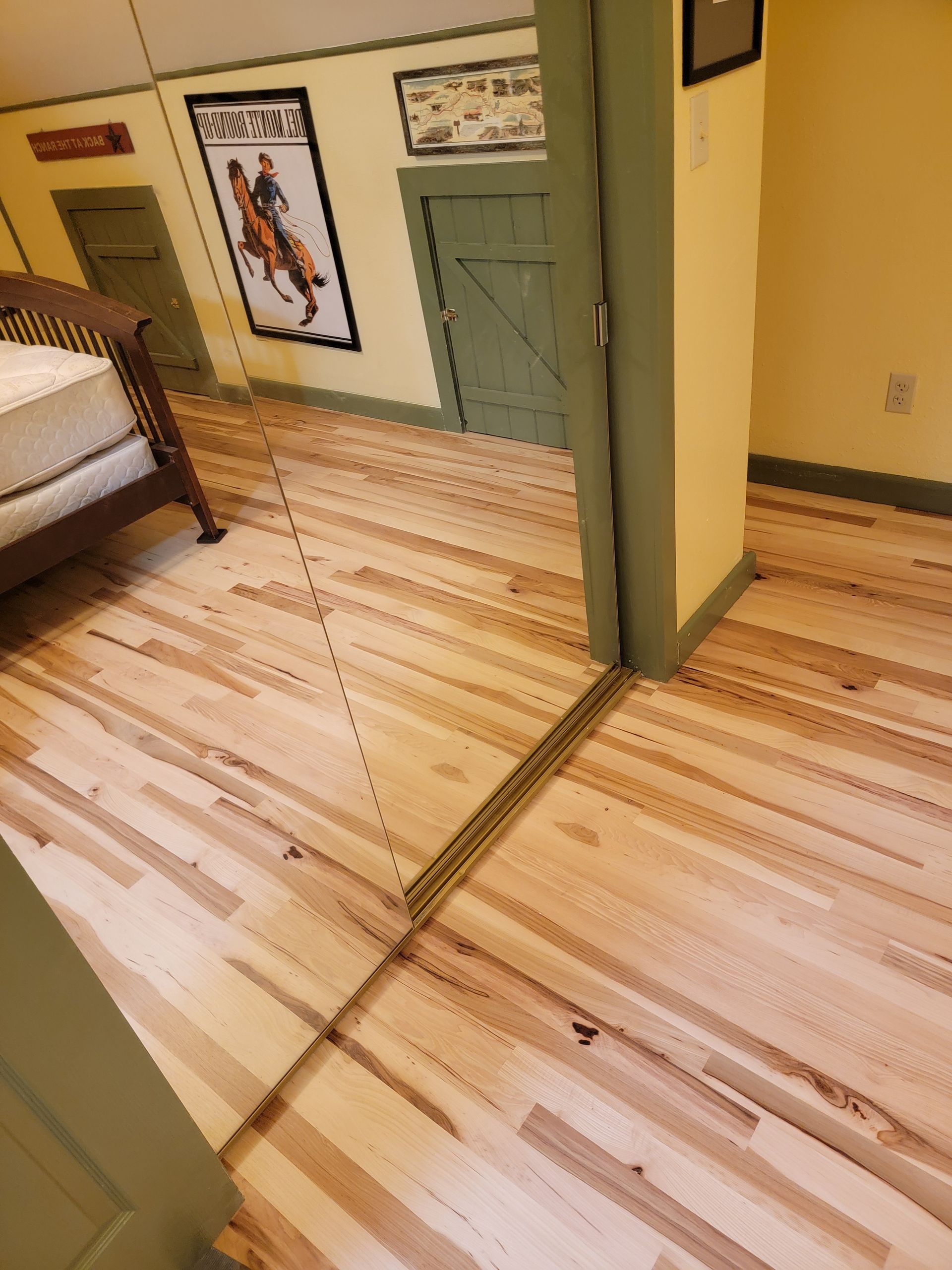 Bedroom with wood floors and a central door opening, viewed from a hallway.