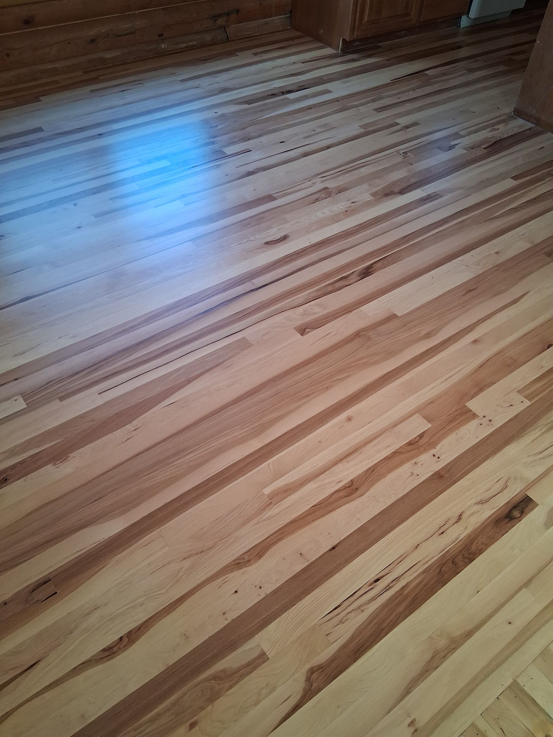 Empty wooden floor with light reflection from a window.