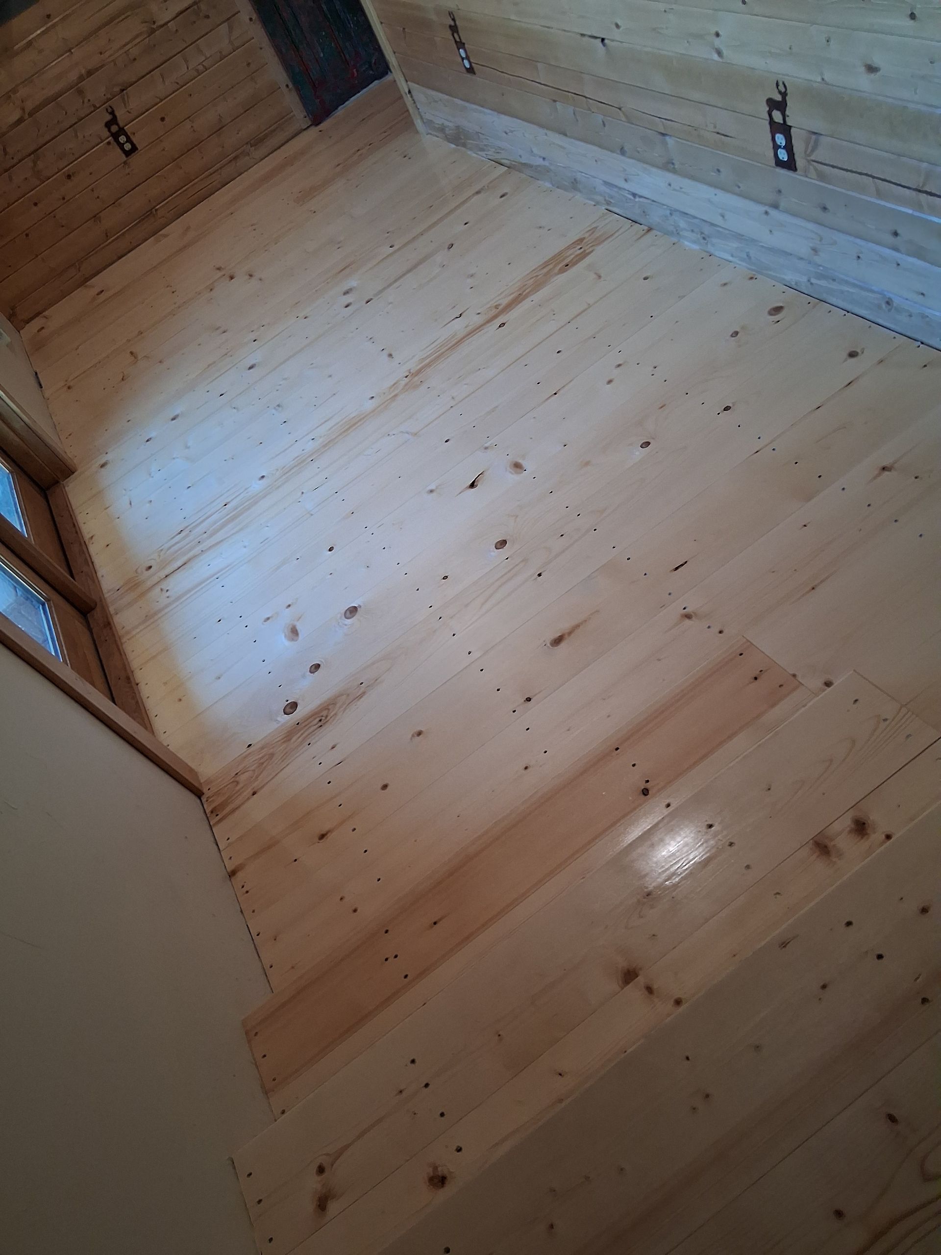 Empty light-wood floor in a small wooden room or closet, viewed from above