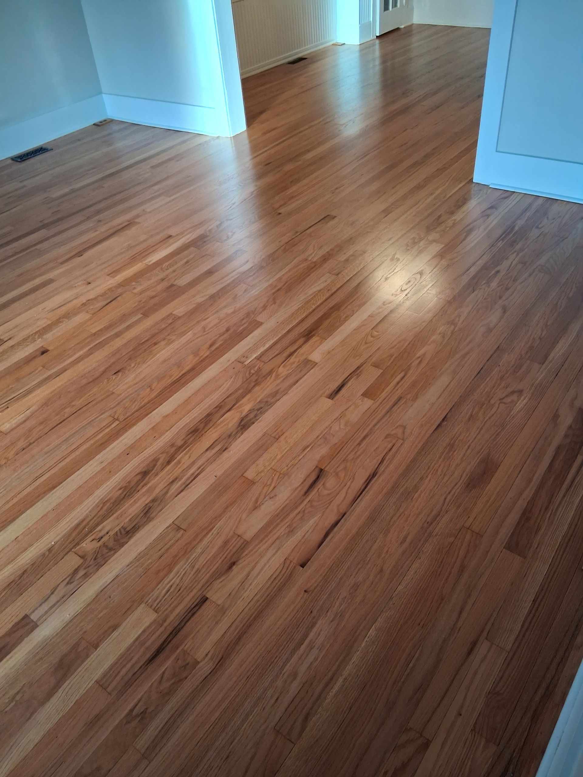 Empty room with shiny hardwood floors and white walls.