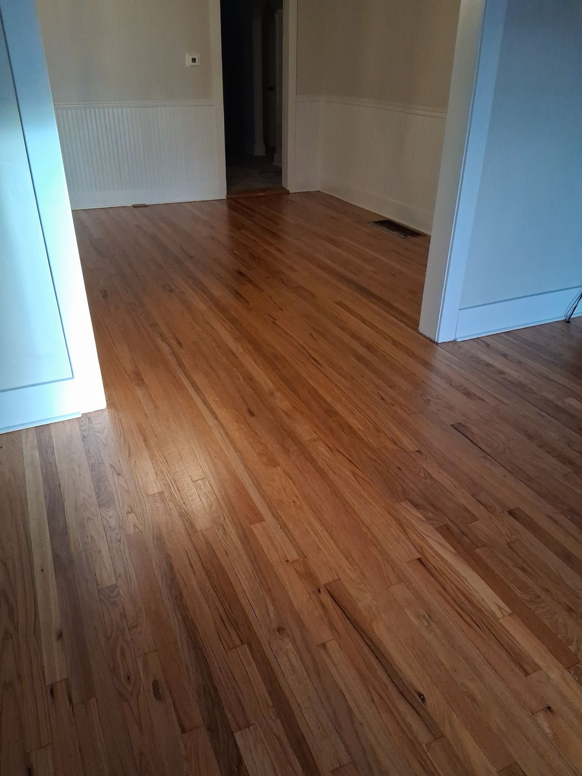 Empty hallway with light wood floors and white walls, viewed from a doorway